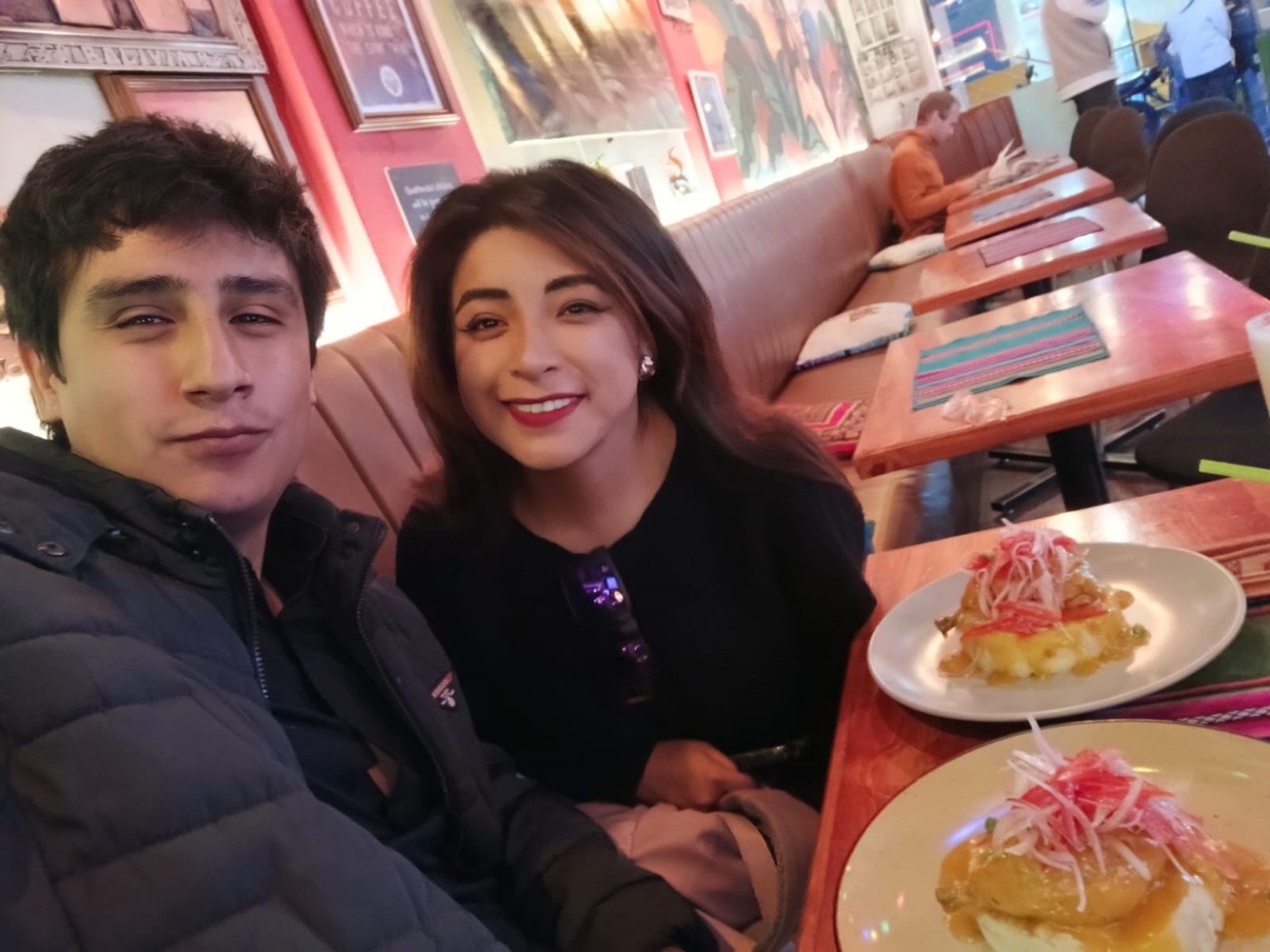Amy y Ricardo compartiendo una comida y sonriendo a la cámara.
